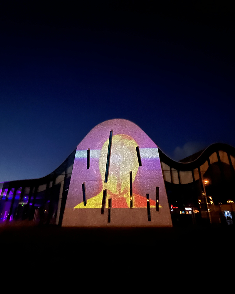 Bâtiment illuminé la nuit avec projection colorée sur la façade