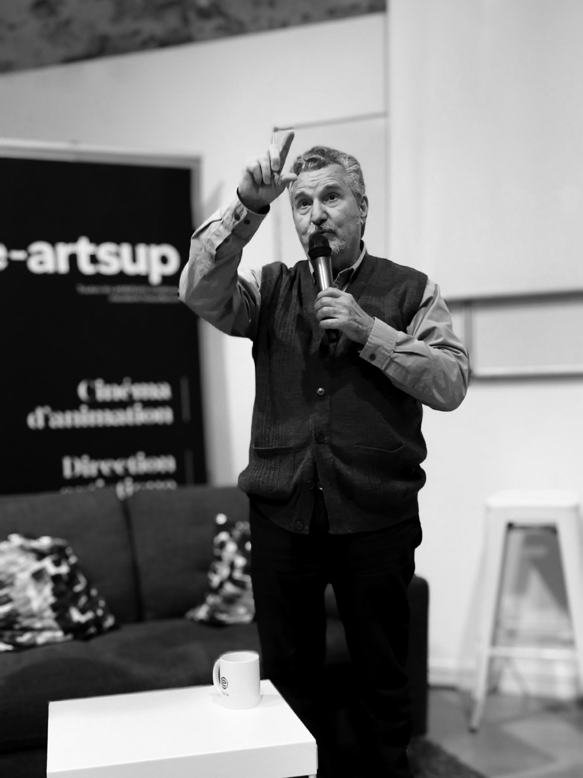 Dan Perri en noir et blanc tenant un micro lors d’une prise de parole.