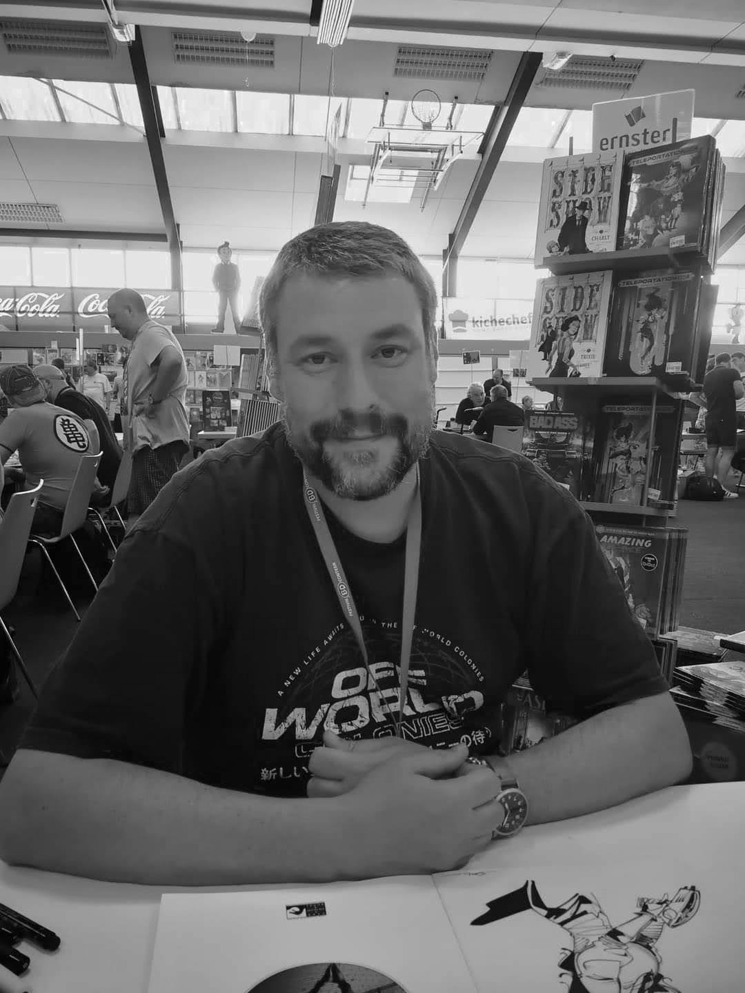 Portrait en noir et blanc de Romain Sordet avec badge dans un espace créatif.