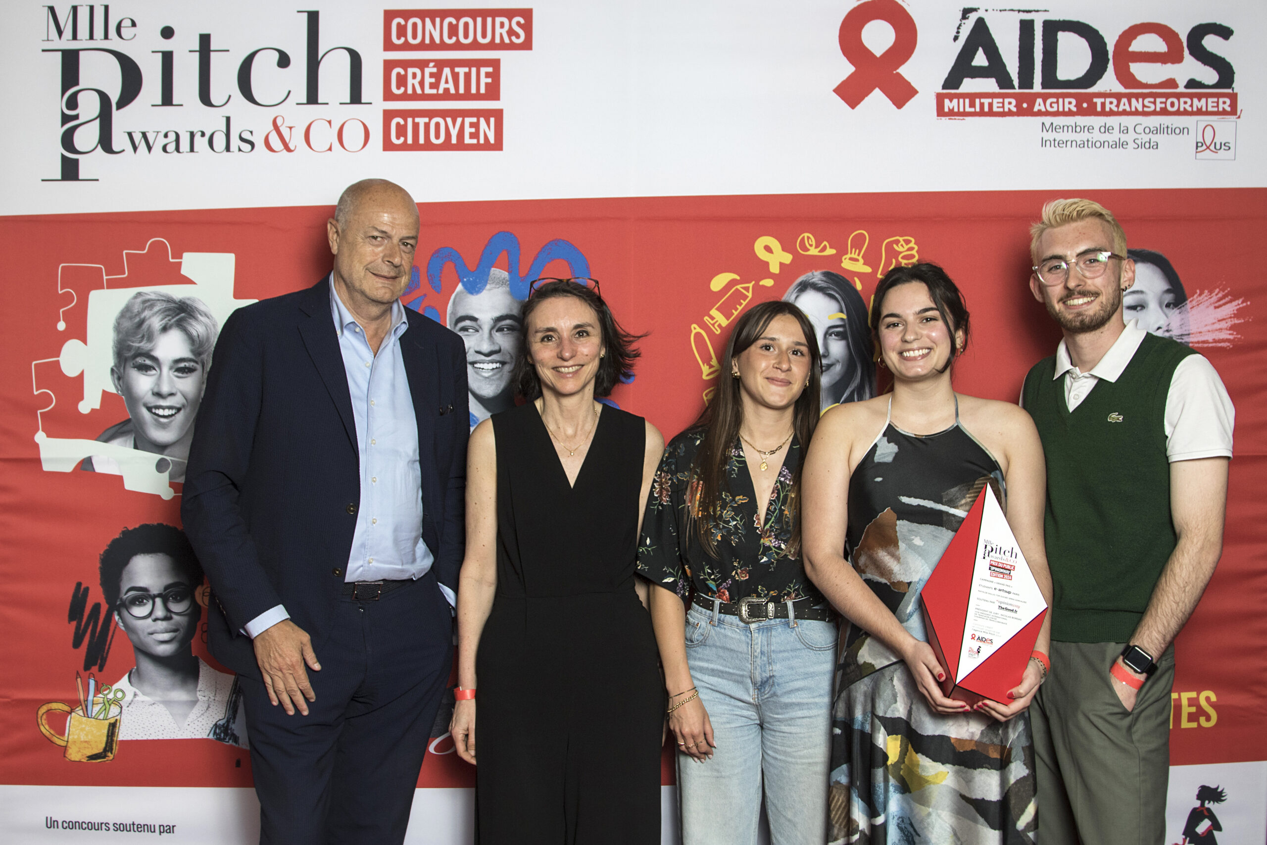 Photo de groupe devant une affiche de concours avec les étudiants et le trophée des Mlle Pitch Awards 2024