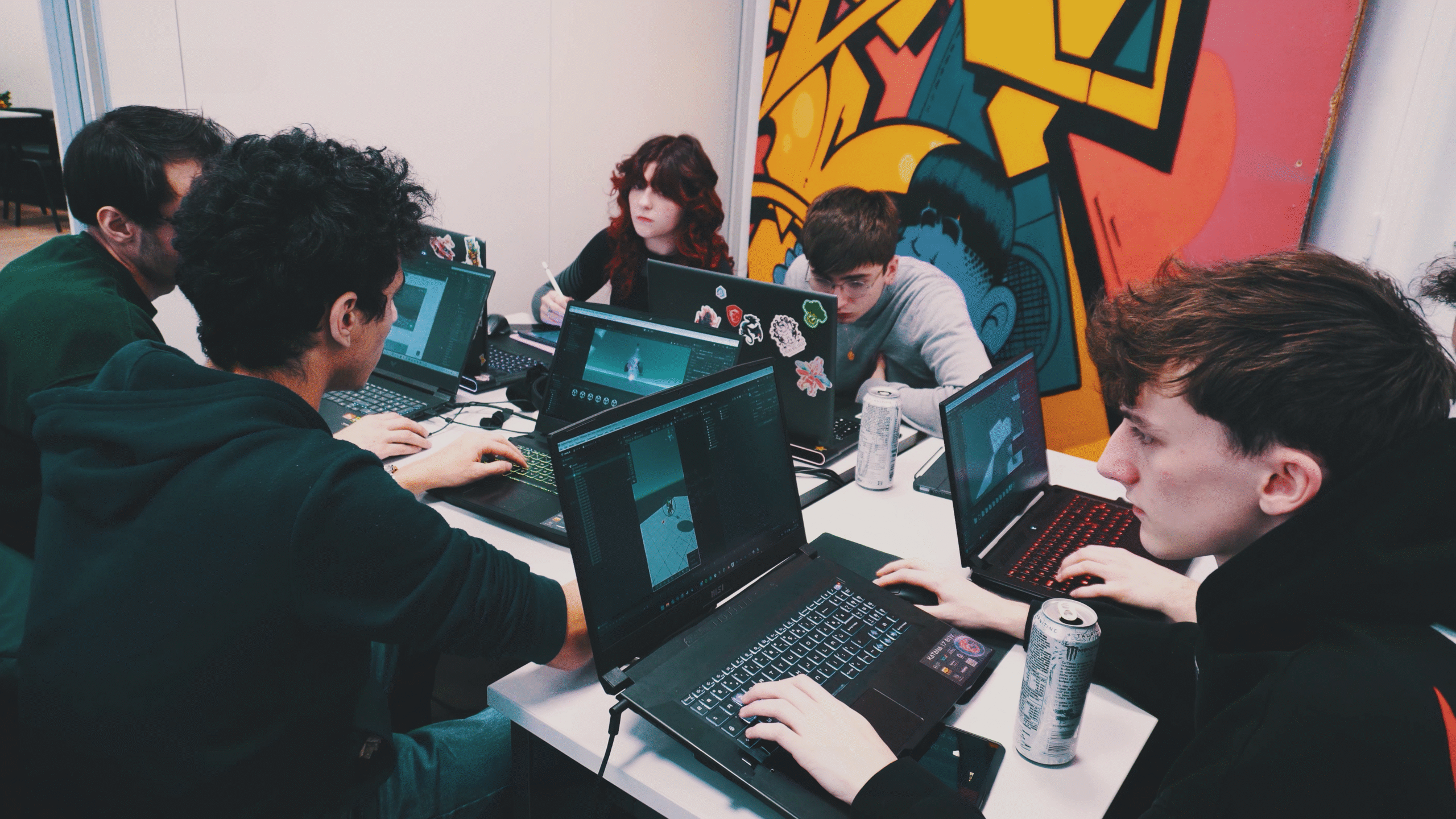 Étudiants travaillant sur un projet autour d’ordinateurs dans une salle de cours.