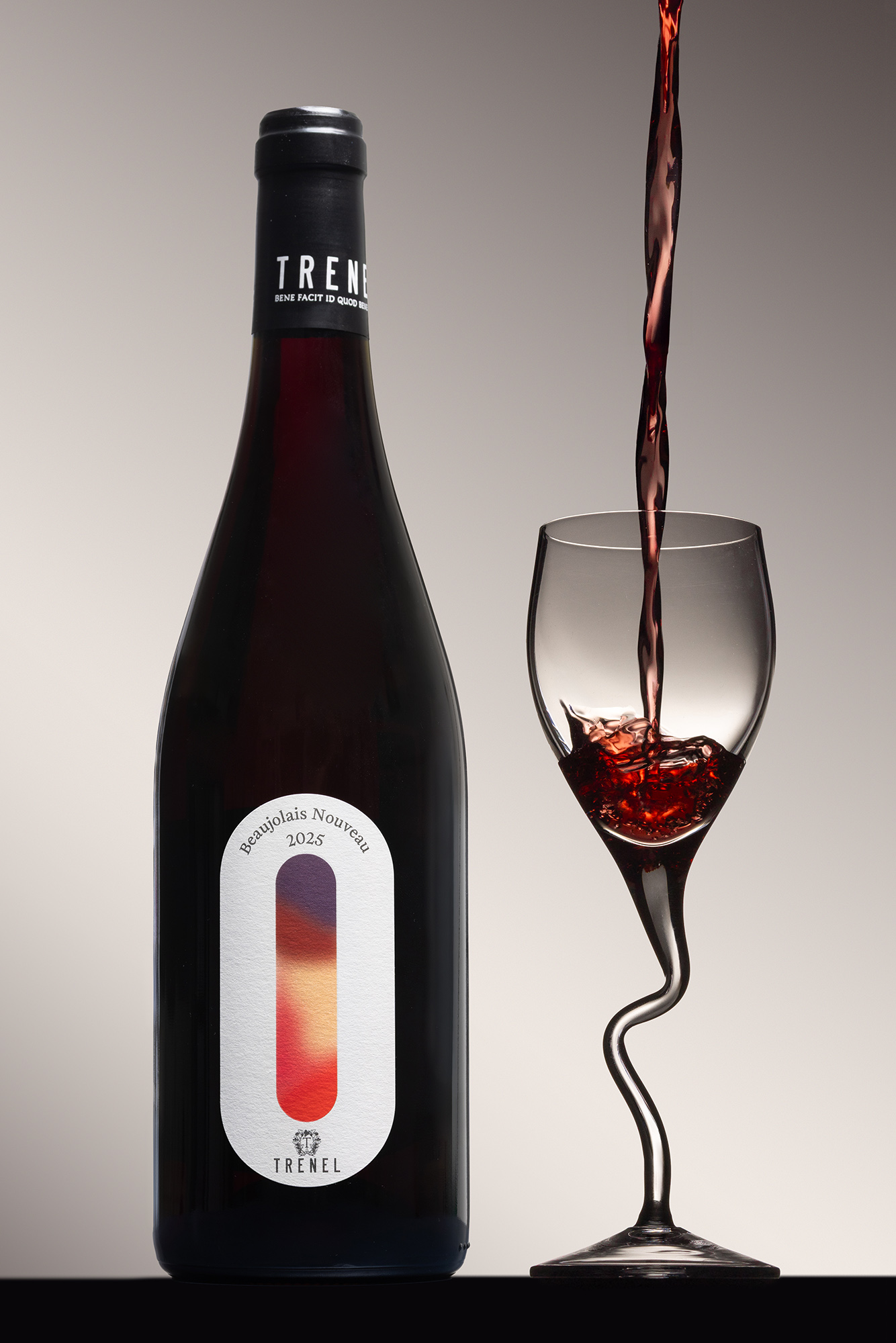 Bouteille de vin rouge avec verre rempli, sur fond clair avec étiquette colorée