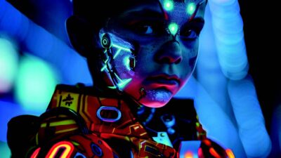 Portrait d’un enfant dans un univers cyberpunk, portant une tenue futuriste lumineuse et des implants technologiques fluorescents sur le visage, éclairé par des néons bleus et violets dans une ambiance de science-fiction.