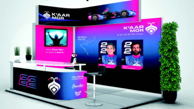 Stand d’exposition aux couleurs bleu et rose néon dédié à une équipe de sport automobile, intégrant écrans, signalétique, identité visuelle et espace d’accueil, projet étudiant de design événementiel et communication de marque.