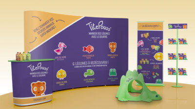 Stand d’exposition coloré conçu pour une marque alimentaire destinée aux enfants, avec mascottes illustrées, supports de communication et mobilier ludique, projet étudiant de design graphique et marketing événementiel.