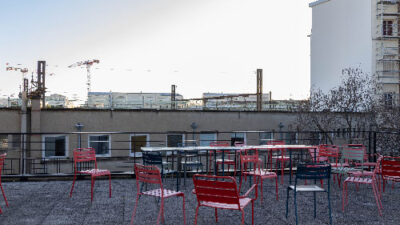 Terrasse extérieure aménagée avec tables et chaises rouges sur le toit du campus