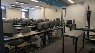 Salle informatique moderne du campus e-artsup avec rangées d’ordinateurs et espace de présentation