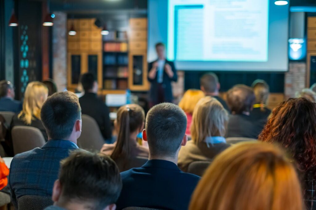 Public assistant à une conférence professionnelle sur l’esport et les métiers du gaming dans une salle de séminaire moderne.