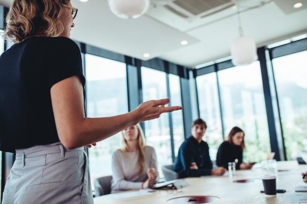 Intervenante présentant un projet en réunion d’entreprise dans un espace de travail moderne et lumineux.