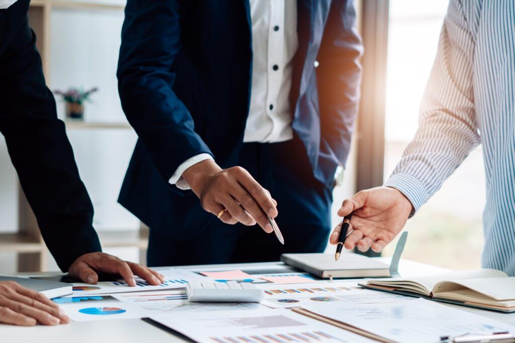 Réunion stratégique en entreprise avec analyse de données et documents financiers autour d’une table de travail.
