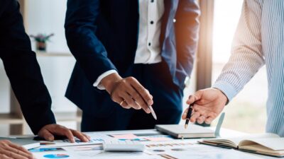 Réunion stratégique en entreprise avec analyse de données et documents financiers autour d’une table de travail.