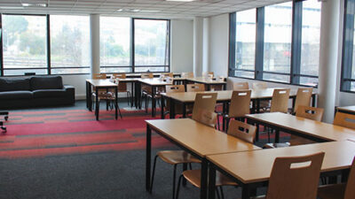 Salle de travail lumineuse avec tables et vue panoramique sur le campus