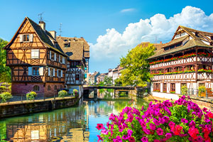 Vue pittoresque du quartier de la Petite France à Strasbourg avec maisons à colombages, canal fleuri et architecture alsacienne traditionnelle sous un ciel ensoleillé