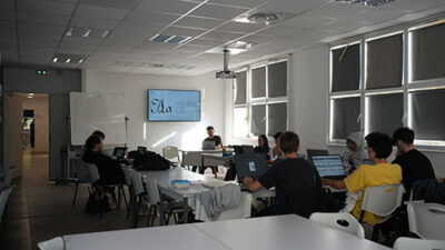 Salle de cours numérique avec étudiants travaillant sur ordinateur portable