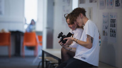 Deux étudiants regardant des photos sur un appareil photo dans les couloirs du campus