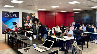Salle de cours collaborative e-artsup avec étudiants travaillant sur ordinateurs et projets créatifs numériques