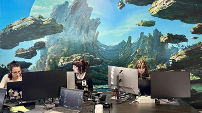 Vue d’étudiantes travaillant sur des ordinateurs devant une fresque immersive inspirée d’un univers fantastique et de science-fiction
