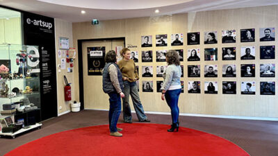 Hall d’accueil du campus e-artsup avec mur de portraits, espace ouvert et étudiants en discussion