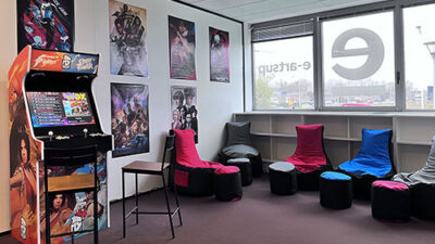 Salle détente gaming du campus avec borne d’arcade rétro, affiches pop culture et assises colorées