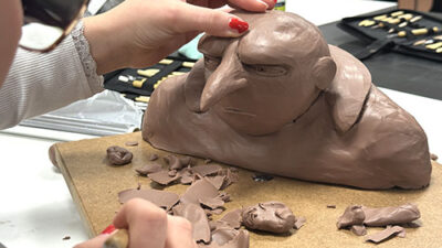 Étudiante sculptant un personnage en argile lors d’un atelier de character design et volume