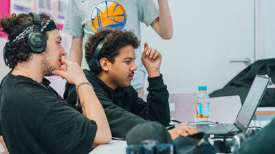 Étudiants concentrés sur un projet numérique avec casque audio en salle de cours