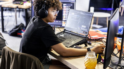 Étudiante travaillant sur ordinateur dans un espace de production numérique et audiovisuelle