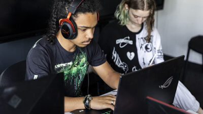 Étudiant travaillant sur ordinateur portable avec casque audio dans une salle dédiée à la création numérique