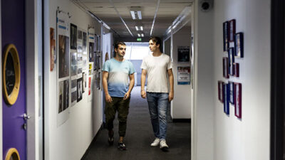 Étudiants marchant dans les couloirs du campus e-artsup Toulouse décorés d’affiches artistiques