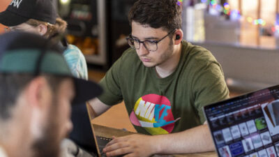 Étudiant concentré sur son ordinateur pendant un atelier de création numérique et design interactif
