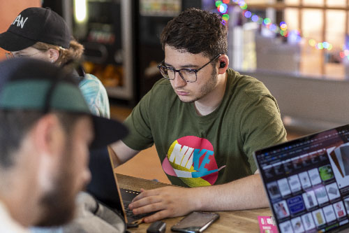 Étudiant concentré sur son ordinateur pendant un atelier de création numérique et design interactif