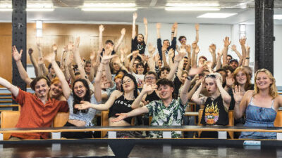 Grand groupe d’étudiants levant les bras dans l’atrium du campus lors d’un événement e-artsup
