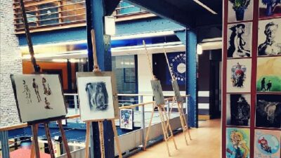 Galerie intérieure du campus avec expositions de dessins, peintures et créations artistiques étudiantes