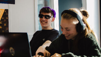 Deux étudiants souriant et travaillant ensemble sur ordinateur en salle de cours
