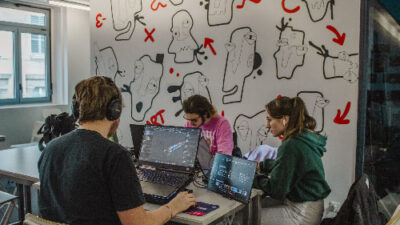 Étudiants travaillant sur des ordinateurs dans une salle de création avec mur illustré