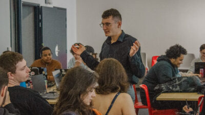 Intervenant échangeant avec des étudiants pendant un cours en salle informatique
