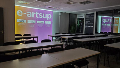 Salle de cours équipée avec projection e-artsup et tables de travail pour les étudiants en création visuelle