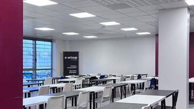 Salle de cours e-artsup moderne avec grandes tables de travail et identité graphique du campus