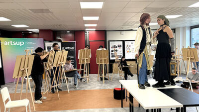 Cours de dessin académique avec modèles costumés et étudiants travaillant sur chevalets dans une salle d’atelier e-artsup