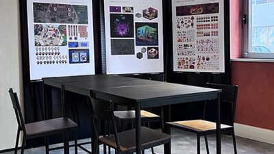 Espace de présentation e-artsup avec affiches de projets étudiants et mobilier haut dédié aux échanges et critiques créatives