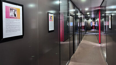 Couloir moderne du campus e-artsup avec salles vitrées et affiches artistiques exposées sur les murs