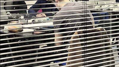 Étudiants travaillant sur ordinateurs dans une salle de création numérique vue à travers des stores