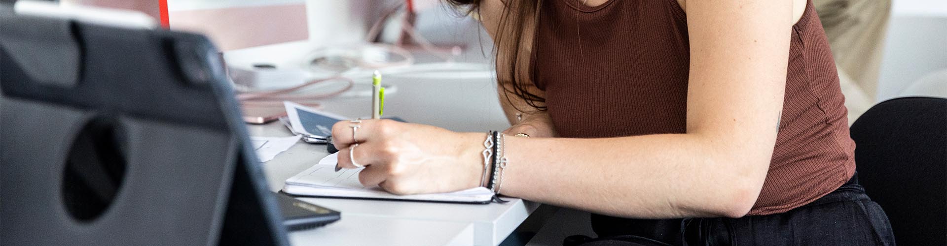 Gros plan sur une femme écrivant dans un carnet de notes avec un stylo sur un bureau.