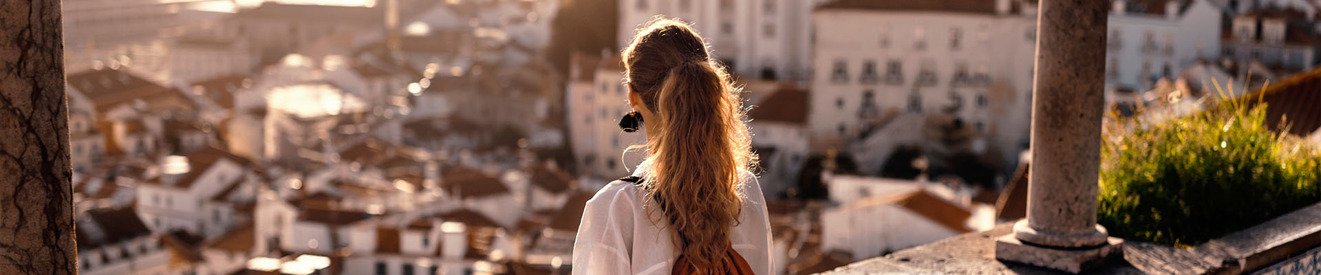 Jeune femme de dos avec un sac à dos admirant la vue panoramique sur les toits de Lisbonne en Europe lors d'un voyage d'études.