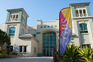 Campus universitaire de la Global Business School (GBS) à Dubaï avec une oriflamme colorée au premier plan.