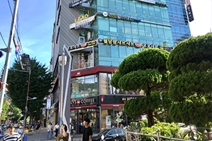 Rue animée de Séoul en Corée du Sud, montrant un grand bâtiment moderne en verre avec des enseignes locales.