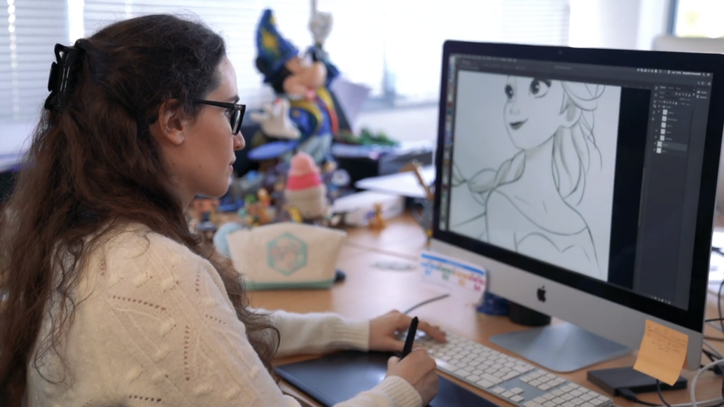 Marylene Pourcelot devant un ordinateur en train de dessiner Elsa sur une tablette graphique