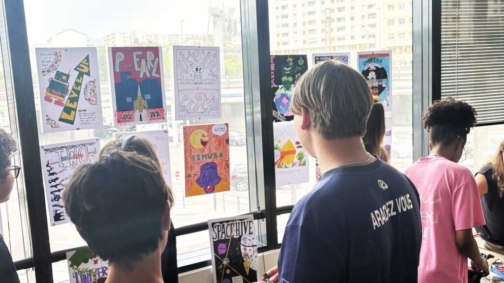 Des lycéens observent les affiches qu’ils ont créées et exposées sur les fenêtres du campus e-artsup Nice.